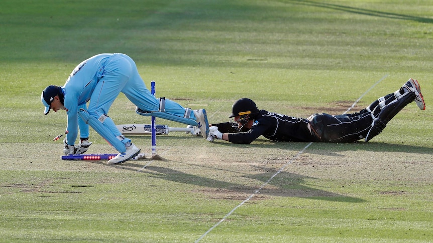 Jos Buttler breaks the stumps as Martin Guptill dives for the crease