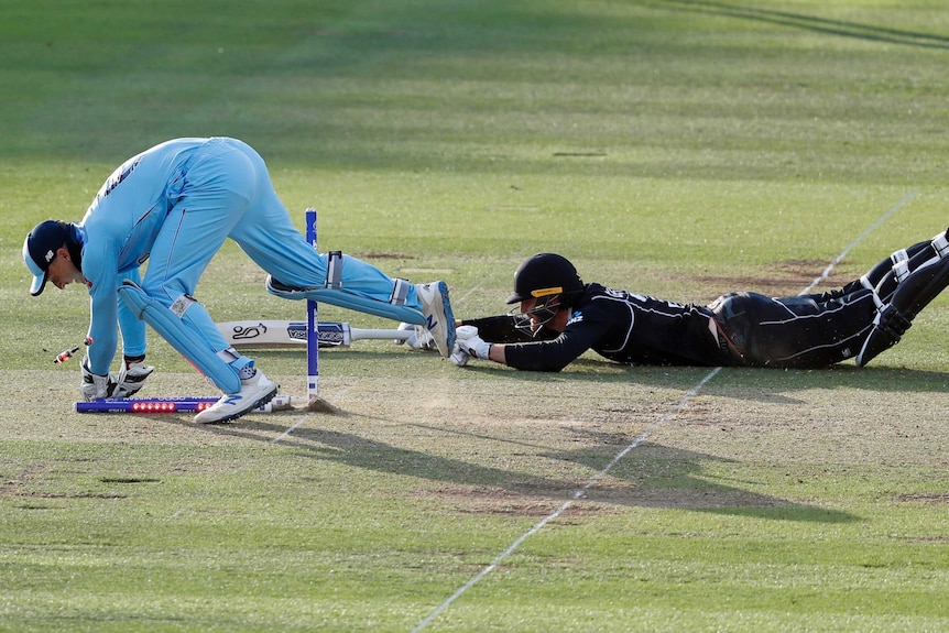 Jos Buttler breaks the stumps as Martin Guptill dives for the crease