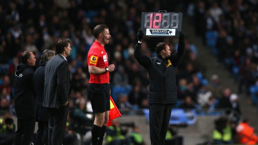 A Premier League official holds up a sign for 12 minutes of injury time.