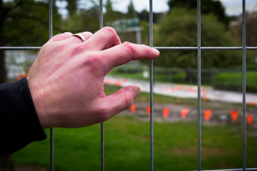 A hand grips a wire fence