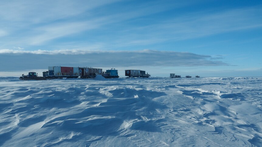 A line of vehicles is seen on the horizon, with vast stretches of snow and ice all around.