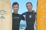 two young men with surfboards on the beach