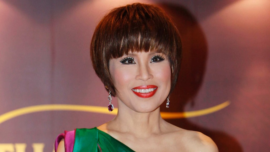 Thai Princess Ubolratana Mahidolm wearing bejewelled earrings and an evening gown, smiles.
