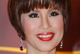 Thai Princess Ubolratana Mahidolm wearing bejewelled earrings and an evening gown, smiles.