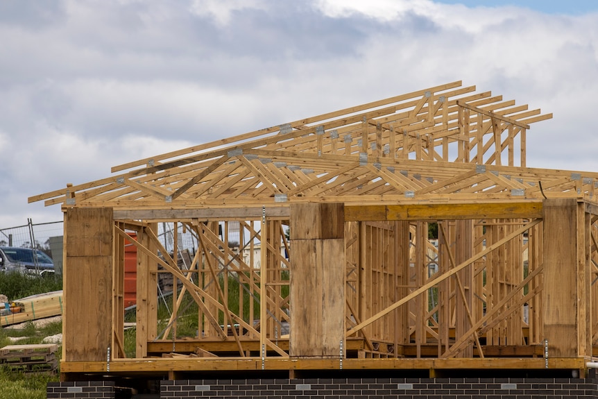 The wooden frame of a house on brown brick foundations on an overcast day