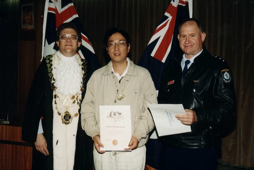 A Chinese man having a picture taken with his citizenship.