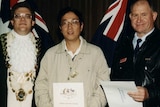 A Chinese man having a picture taken with his citizenship.