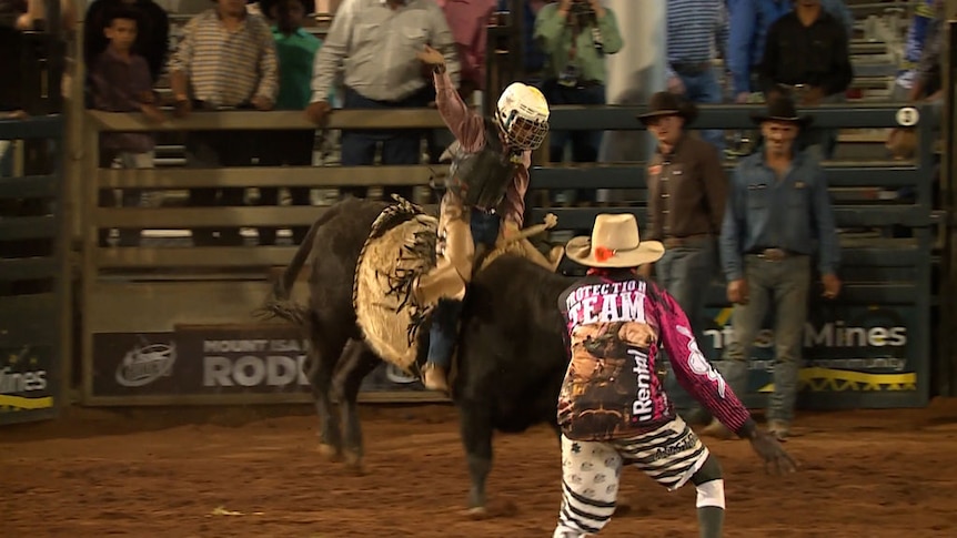 A young rider holds on as a bull bucks in the rodeo ring.