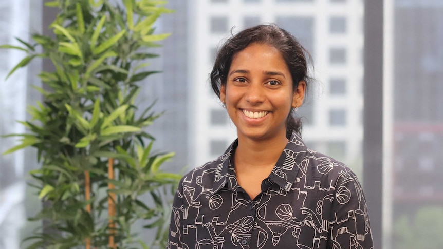 Remya Ramesh smiles while standing in an office, for a story on setting career goals.