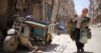 A boy walks along a damaged street at the city of Douma