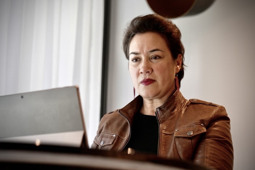 An Aboriginal woman with short brown hair sitting at her computer