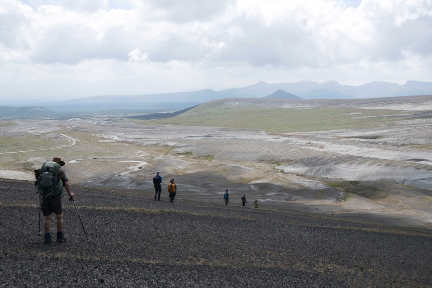 People trekking across a vast plateau.