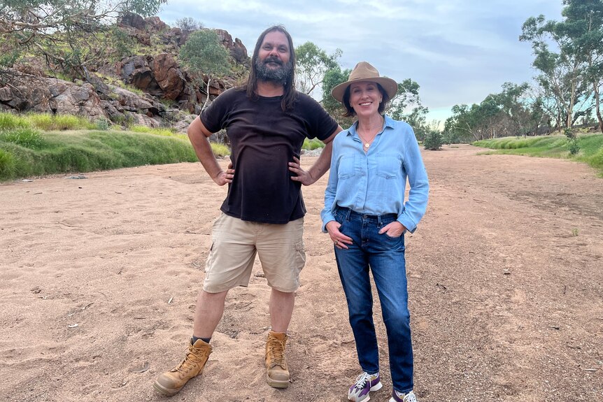 Warwick Thornton, an Aboriginal man, hands on his hips, stands beside Virginia Trioli, wearing a cowboy hat, in the Top End.