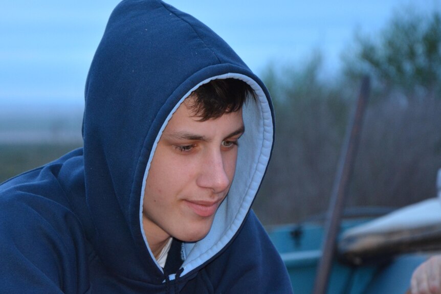 An adolescent male wears a hoodie.