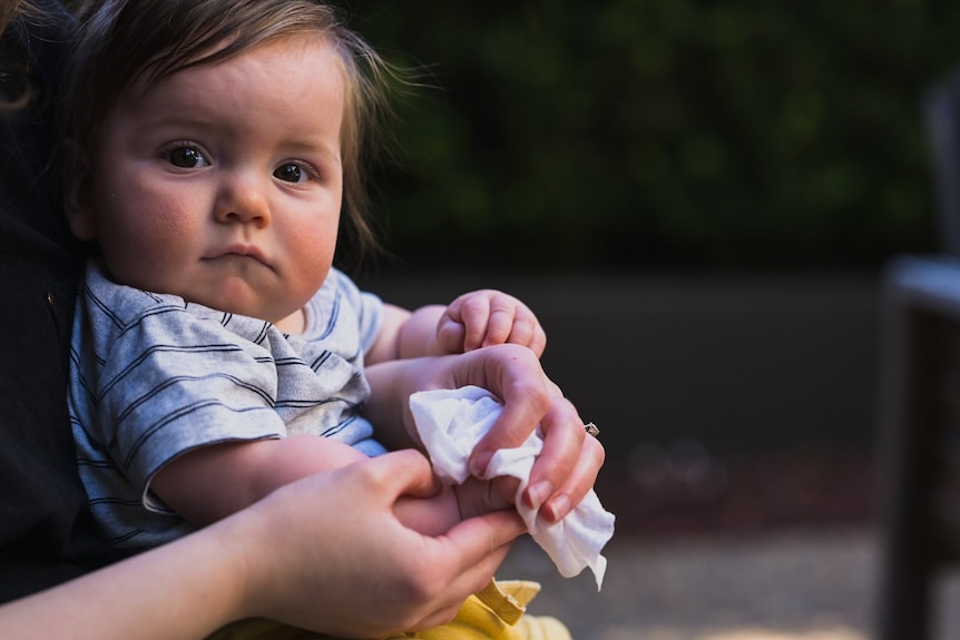 Baby has its hands wiped with wet wipes.