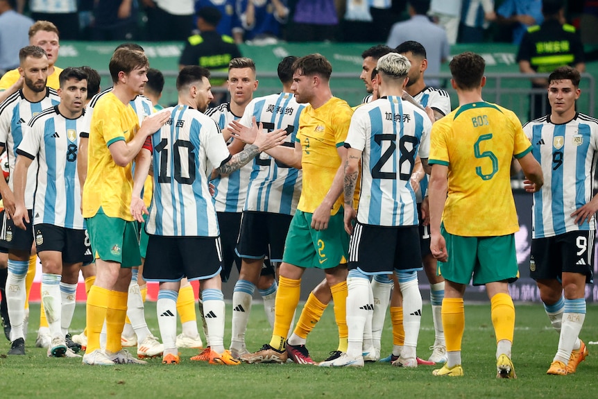 Argentina and Australia soccer team members shake hands after game.