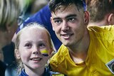 A soccer player smiles at fan taking a photo alongside a smiling young female fan
