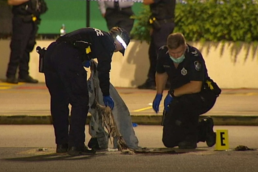 Police wearing facemasks hold a bloody sheet