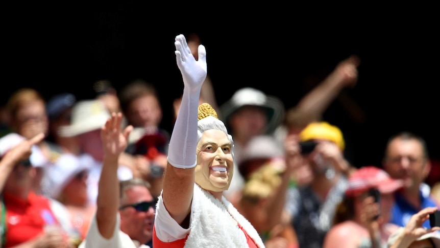 A person wearing a mask depicting Queen Elizabeth II is seen in the crowd