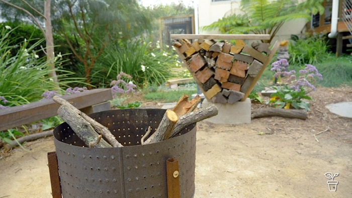Outdoorfirepit and wood pile in a frame in a a backyard garden.