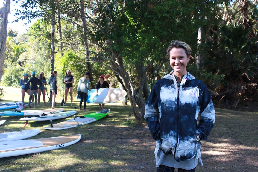 Kayaker Hayley Talbot standing in front of Stand-up paddle boards at Women's Adventure Summit.