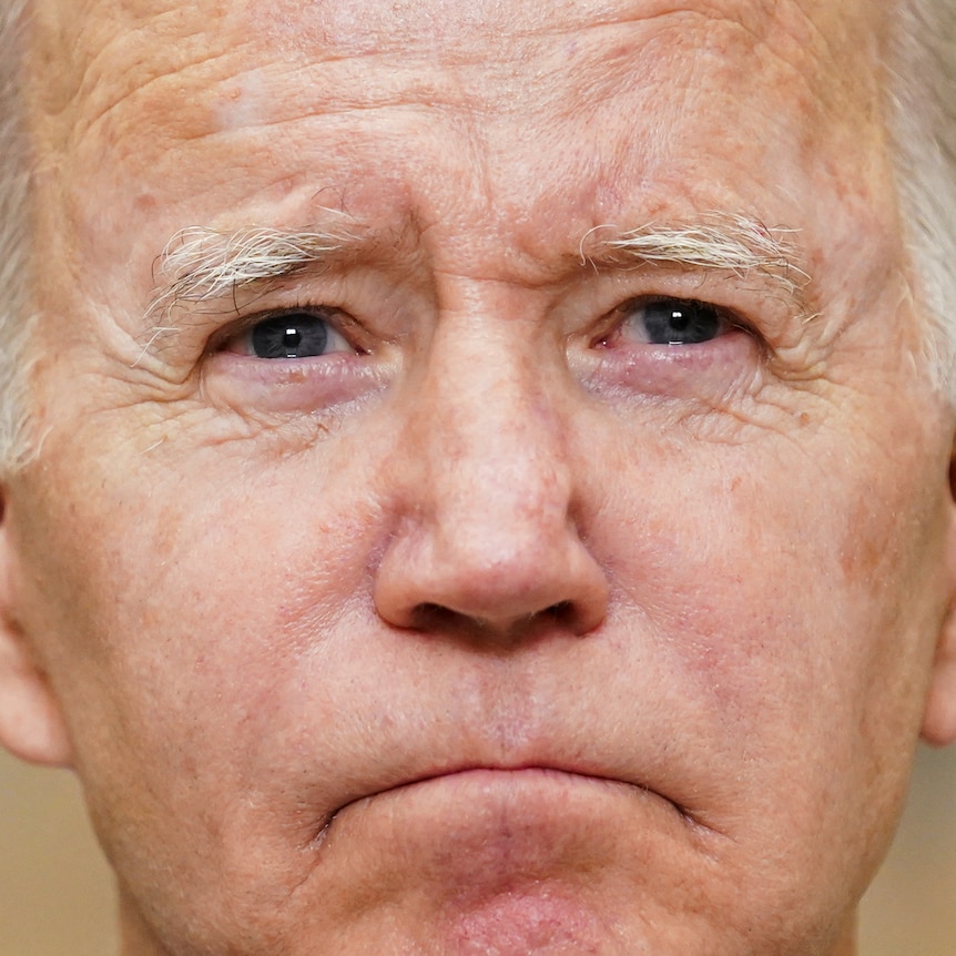 A tight portrait of Joe Biden's face. He looks solemn 