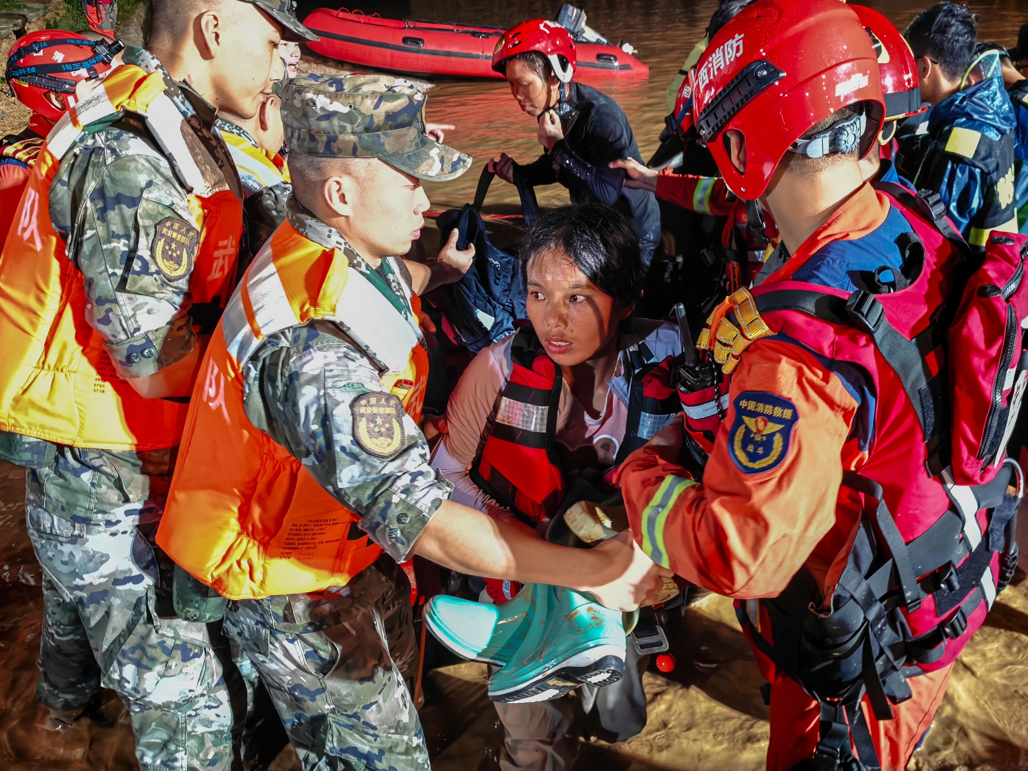 A woman is carried from a boat by several rescue personnel.