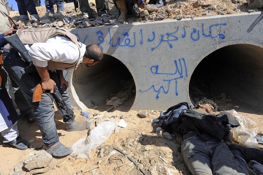An NTC fighter looks through a large concrete pipe where Moamar Gaddafi was allegedly captured on October 20, 2011.
