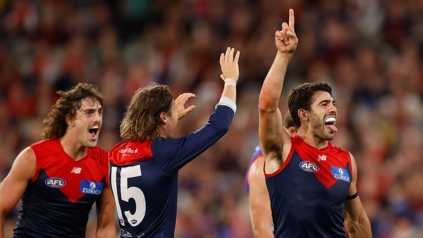 Christian Petracca sticks his tongue out and puts his finger up as Ed Langdon and Luke Jackson celebrate with him