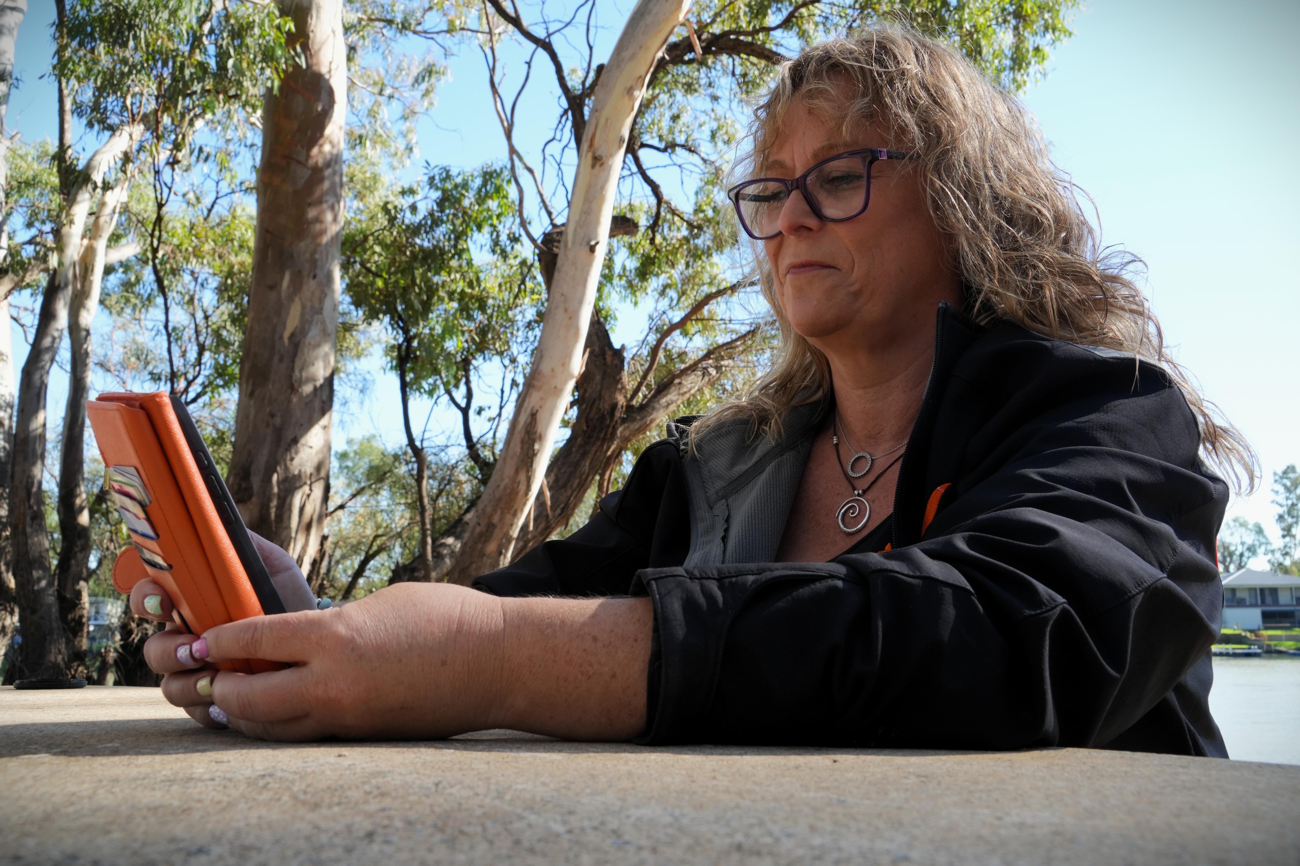 Afuera, una mujer navega en su teléfono celular. 