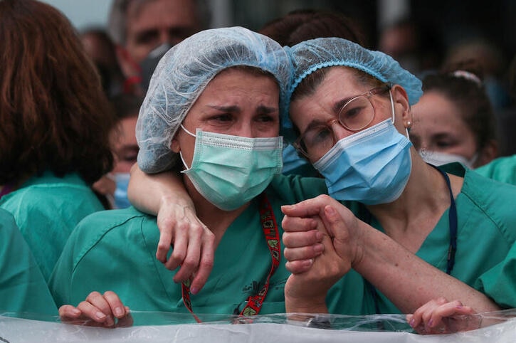 Two female nurses crying while holding hands
