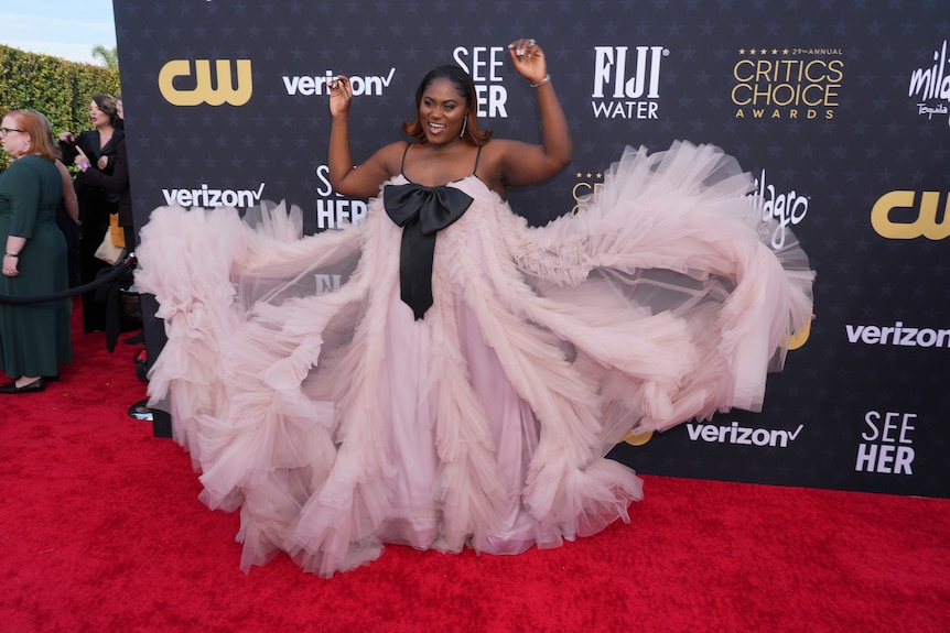 Danielle Brooks wearing a dusty pink gown tulle-draped with a big black bow on the front. Her tulle fans out like a flower