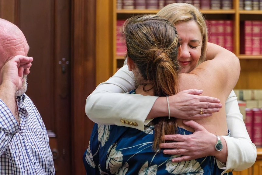 Anastacia Palaszczuk hugs Belinda Beasley while a teary Brett Beasley stands nearby.