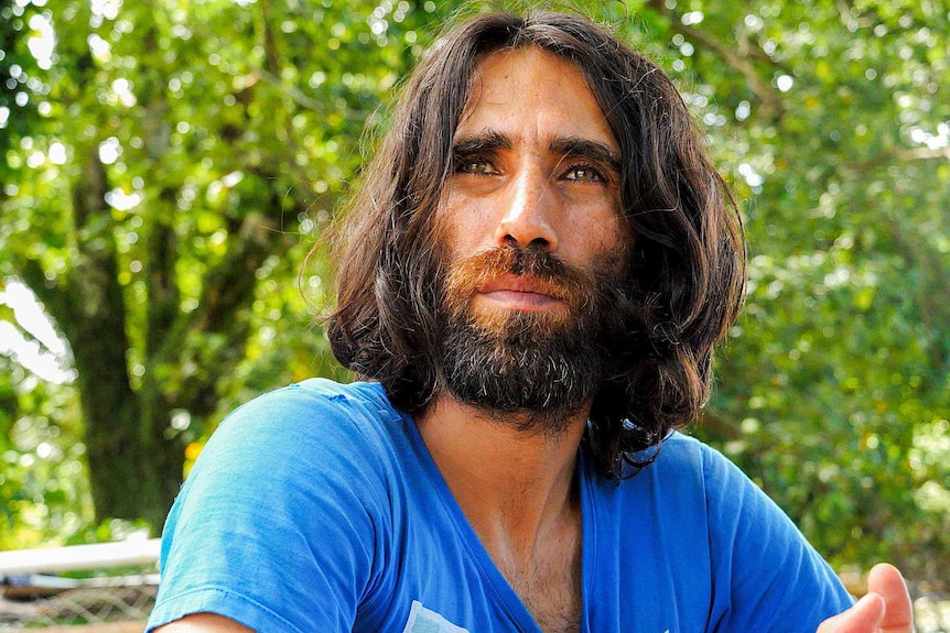 A picture of a long-haired man wearing a t-shirt.