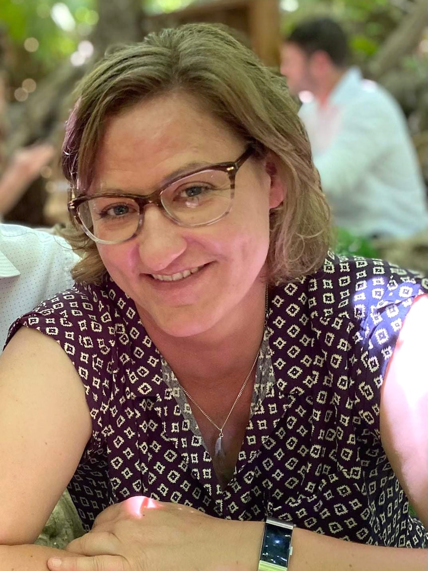 A woman wearing glasses and a purple dress smiles
