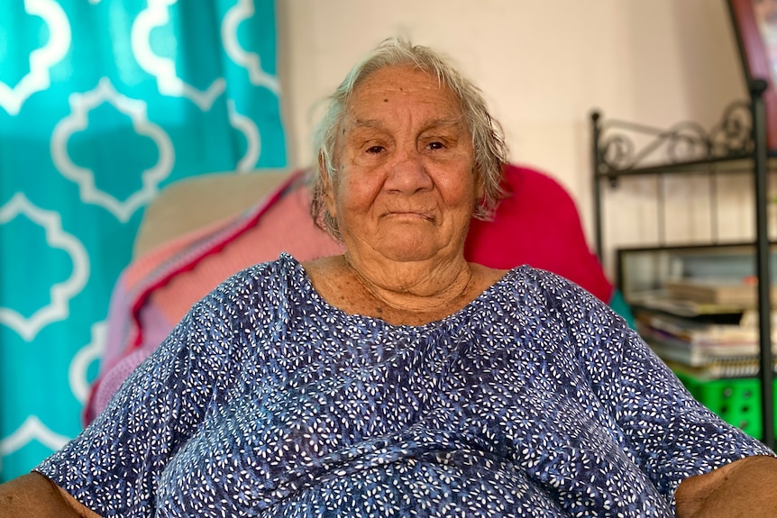 An elderly woman sits in an armchair. 