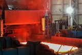 A hot steel plate exits the milling press