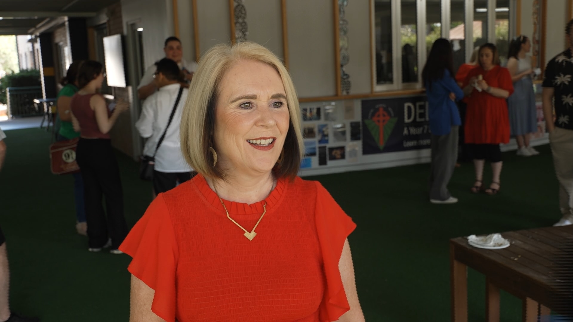 Una mujer rubia con una camisa roja y lápiz labial rojo.