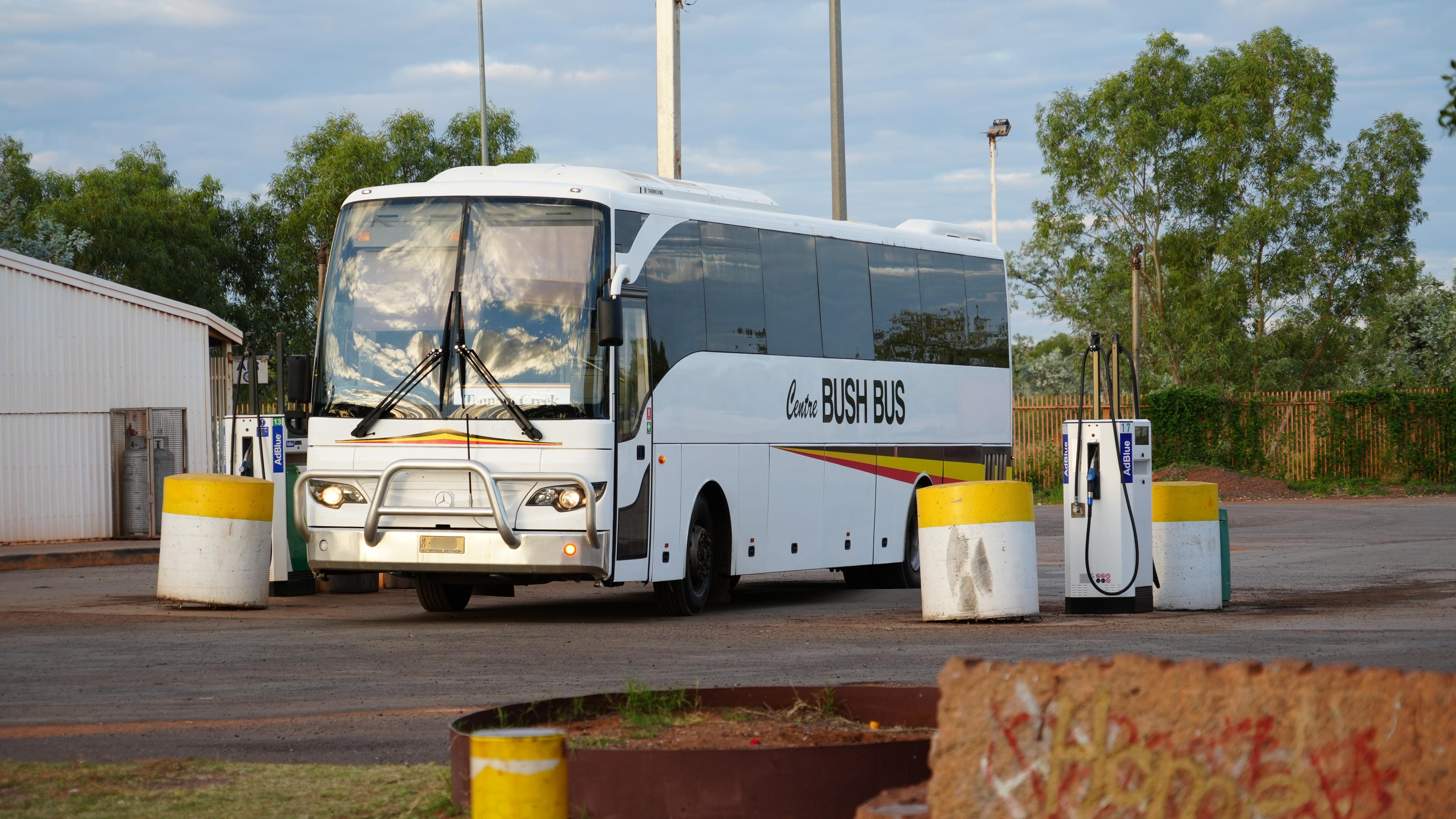 A white large passenger bus at a petrol station, with the words' Centre Bush Bus' printed on the vehicle.