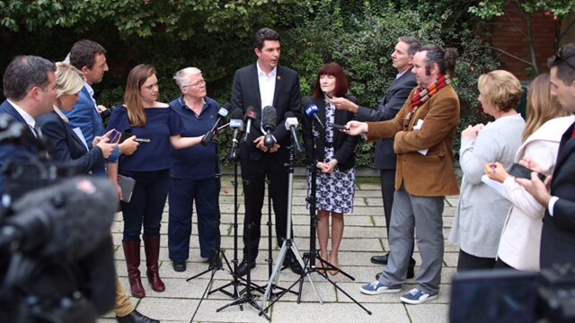 A wide shot of Scott Ludlam flanked by colleagues and reporters in the Fern Garden at WA's Parliament House.
