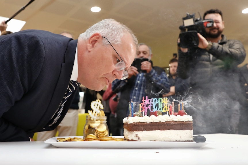 Man blows out candles on birthday cake 