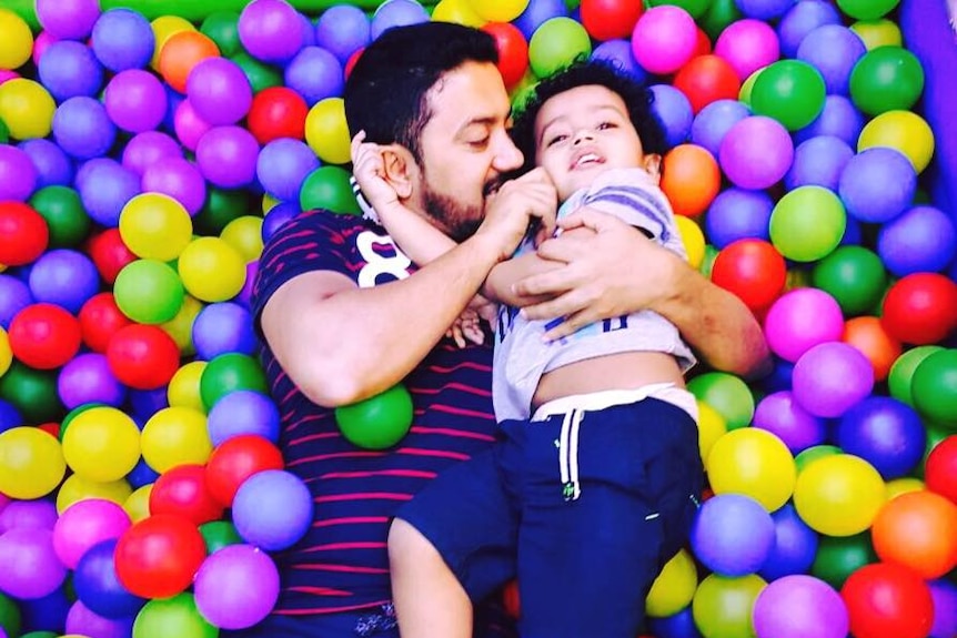 Tauqeer and his son laying in a colourful ball pit.