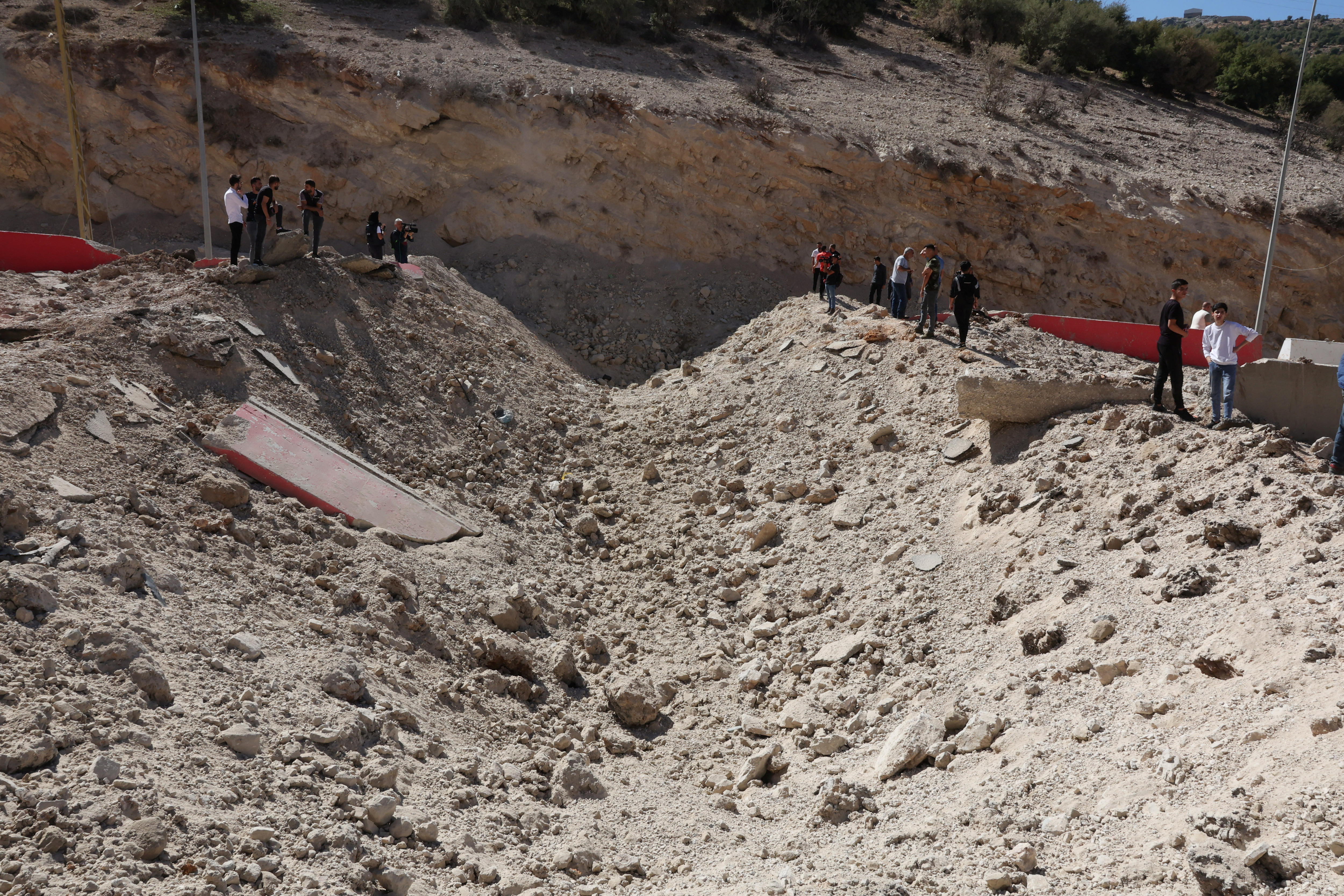 A hole in the dusty ground, with people standing on either side.