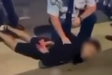 A man on the floor with a policeman holding him down 