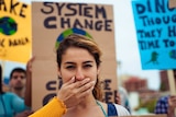 A woman with a hand over her mouth during a protest.