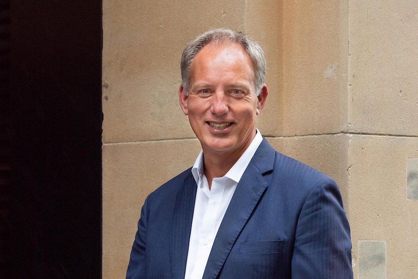 A man in a blue suit smiles at the camera