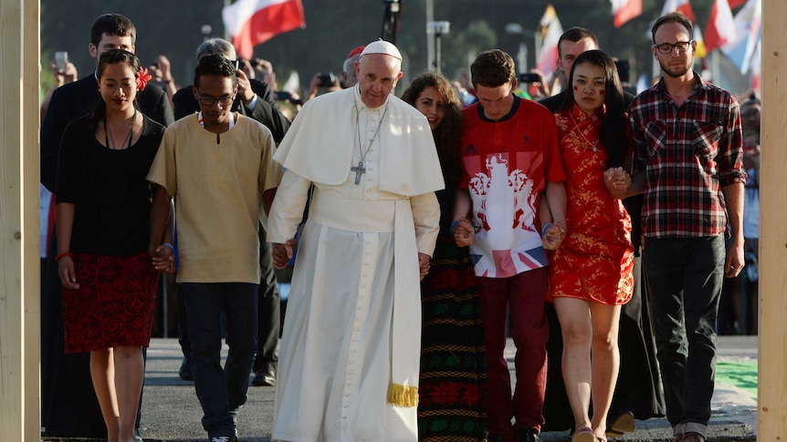 Pole Francis walks in a line holding hands with young men and women.