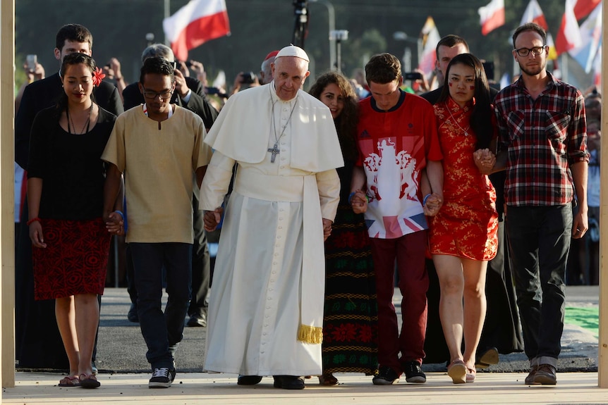 Pole Francis walks in a line holding hands with young men and women.