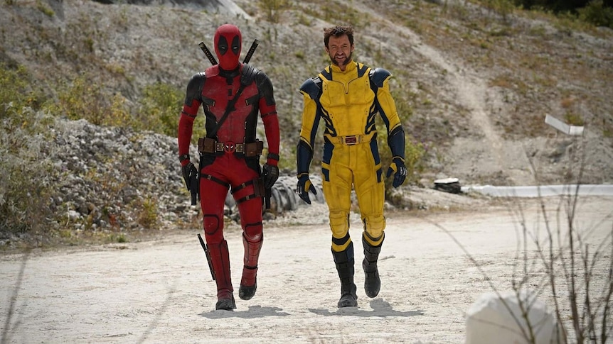 Comic book characters Deadpool and Wolverine walk towards the camera in full costume.
