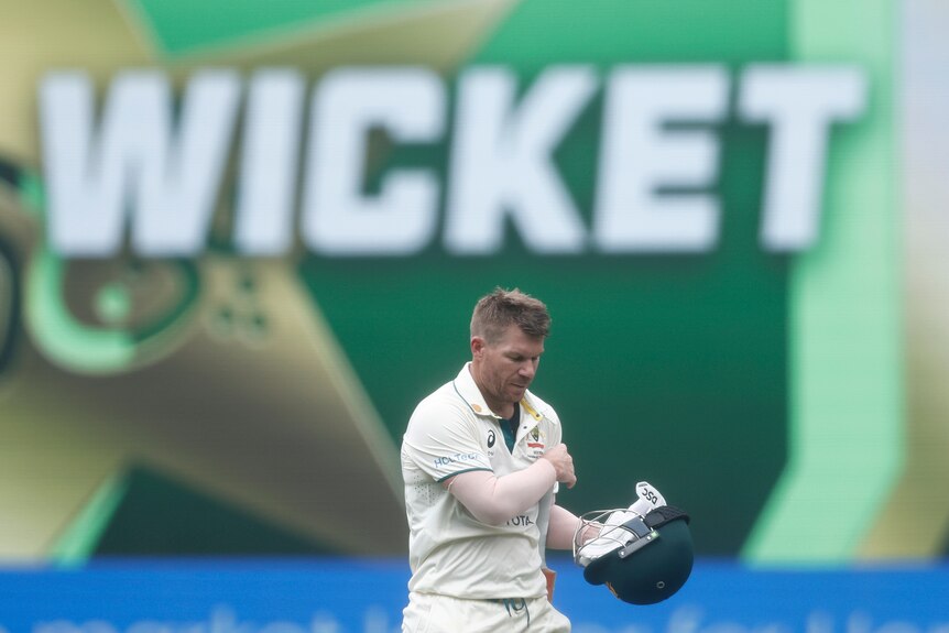 David Warner walks off in front of a wicket banner